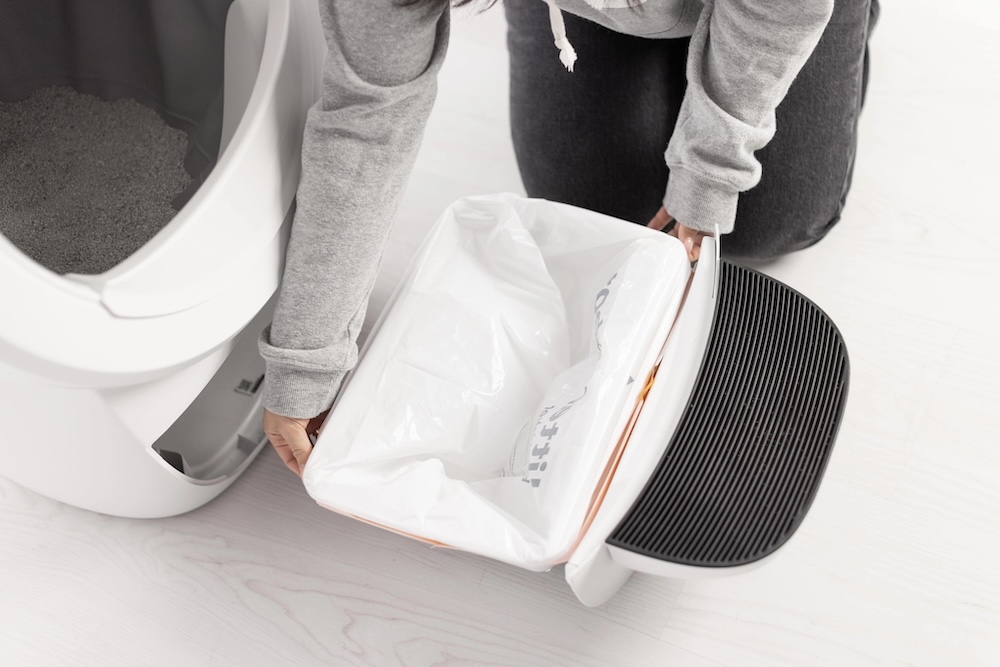 Pushing the remainder of the bag into the bottom of the Litter-Robot 4 Waste Drawer and then sliding the waste drawer closed.